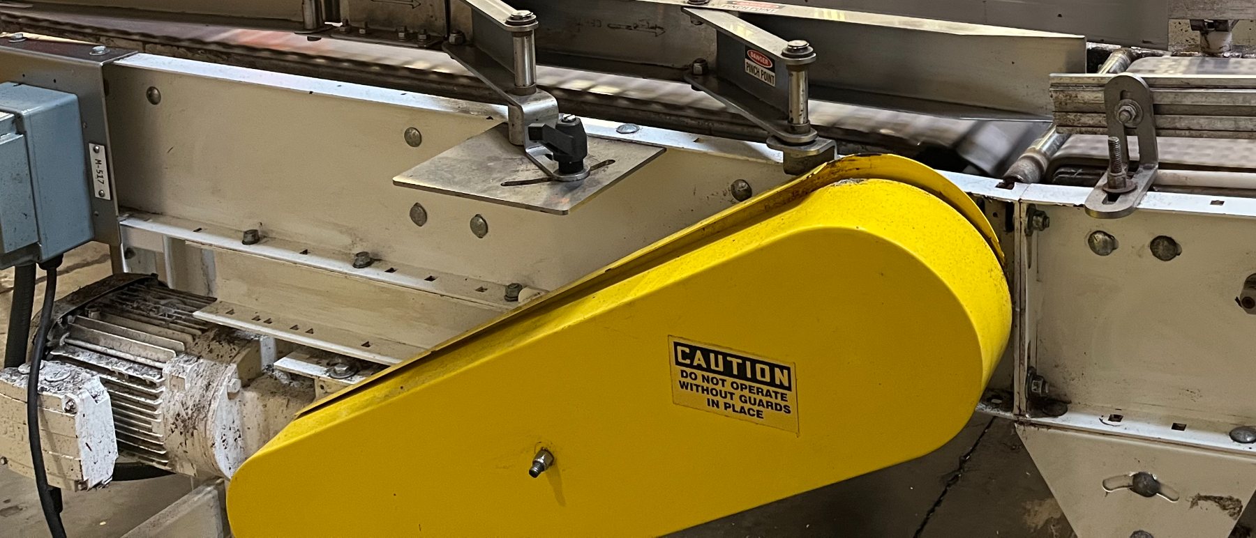 Yellow drive guard on a case conveyor in a high-speed beverage plant