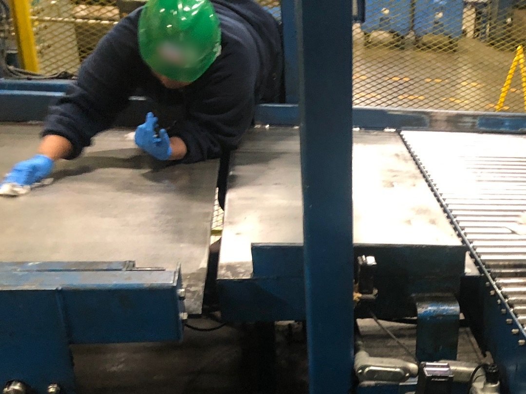 Operator in a hard hat working at a roller conveyor during a line walk